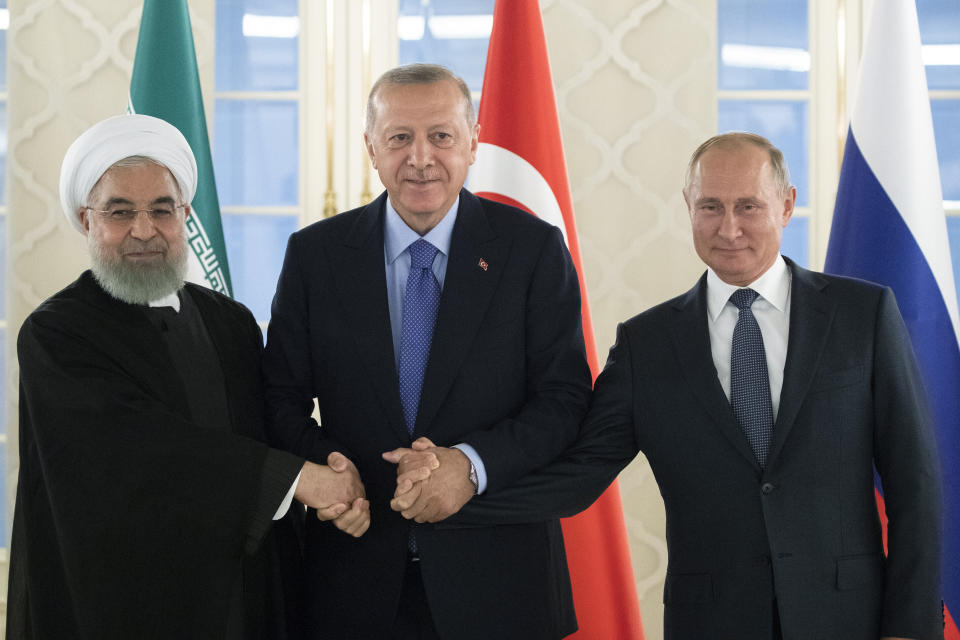 FILE - This Sept. 16, 2019 file photo, from left: Iranian President Hassan Rouhani, Turkish President Recep Tayyip Erdogan and Russian President Vladimir Putin shake hands during their meeting in Ankara, Turkey. America maintains some 1,000 troops in Syria who work alongside the Kurdish fighters. America’s foes -- Assad, Russia, and Iran -- all stand to gain from a U.S. troop withdrawal in Syria and will likely bide their time until they can move in and retake the area. (AP Photo/Pavel Golovkin, Pool, File)