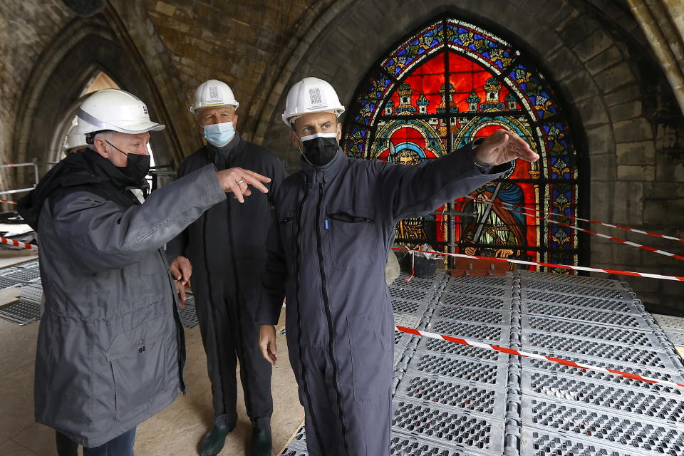 French President Emmanuel Macron speaks with a worker and the French Army General Jean-Louis Georgelin in front of a stained glass window under the damaged vaults during a visit at the reconstruction site of the Notre-Dame de Paris Cathedral, which was damaged in a devastating fire two years ago, as restoration works continue, in Paris, France, April 15, 2021. Ian Langsdon/Pool via REUTERS