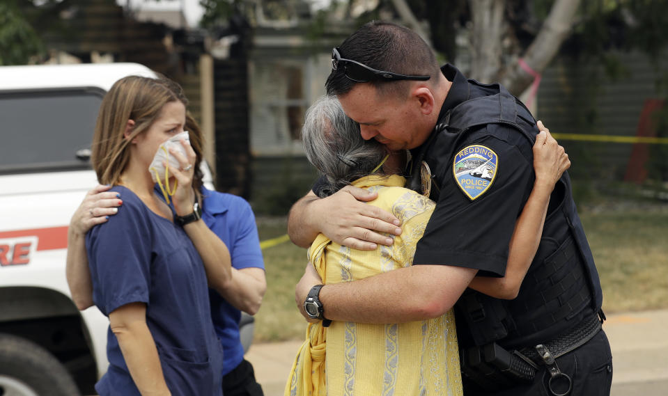 Redding Police Dept. officer Brian Berg, right, comforts a resident, center, wishing not to be identified, after she saw her fire-ravaged home for the first time Thursday, Aug. 2, 2018, in Redding, Calif. (AP /Photo/Marcio Jose Sanchez)