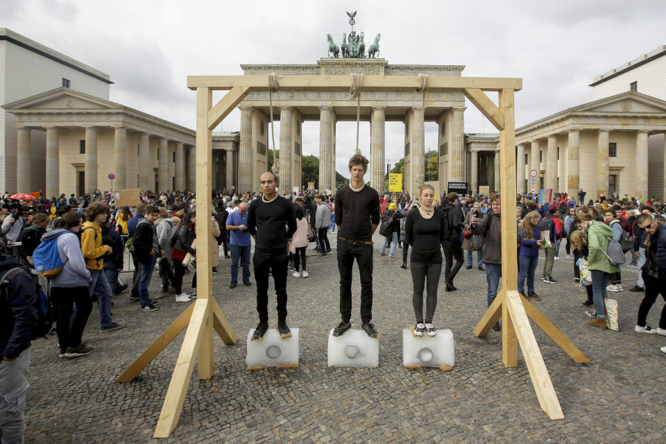 Three persons stand on ice blocks under gallows to protest against the climate policy prior to a 'Friday for Future' climate protest in front of the Brandenburg Gate in Berlin, Germany, Friday, Sept. 20, 2019. Protests of the 'Friday For Futurte' movement against the increase of carbon dioxide emissions are planned Friday in cities around the globe. In the United States more than 800 events were planned Friday, while in Germany more than 400 rallies are expected. (AP Photo/Markus Schreiber)