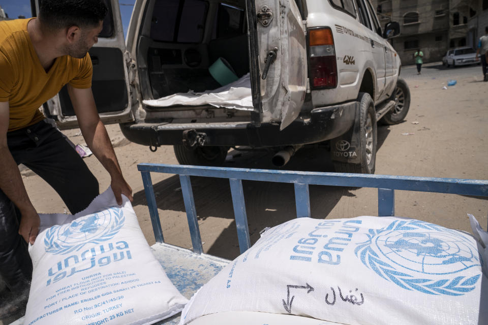 Bags of foodstuffs provided by the United Nations Relief and Works Agency for Palestine Refugees in the Near East (UNRWA) are loaded into the back of a vehicle as Palestinians collect food aid following a cease-fire reached after an 11-day war between Gaza's Hamas rulers and Israel, in Gaza City, Saturday, May 22, 2021. (AP Photo/John Minchillo)