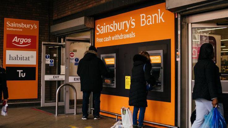 People using ATMs under a Sainsbury's Bank sign