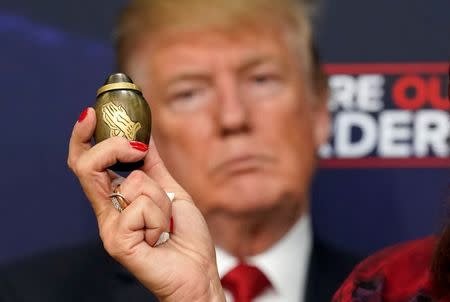 A woman holds an urn containing her son's remains as U.S. President Donald Trump holds an "Angel Families" meeting with victims of illegal immigration at the White House in Washington, U.S., June 22, 2018. REUTERS/Kevin Lamarque