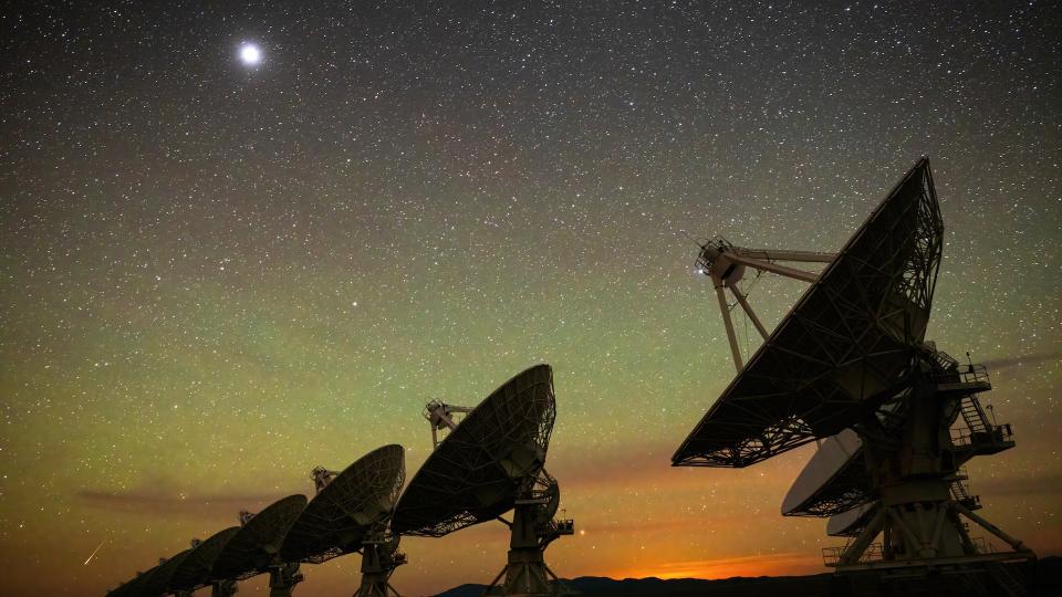 large satellite dishes point up into the night sky