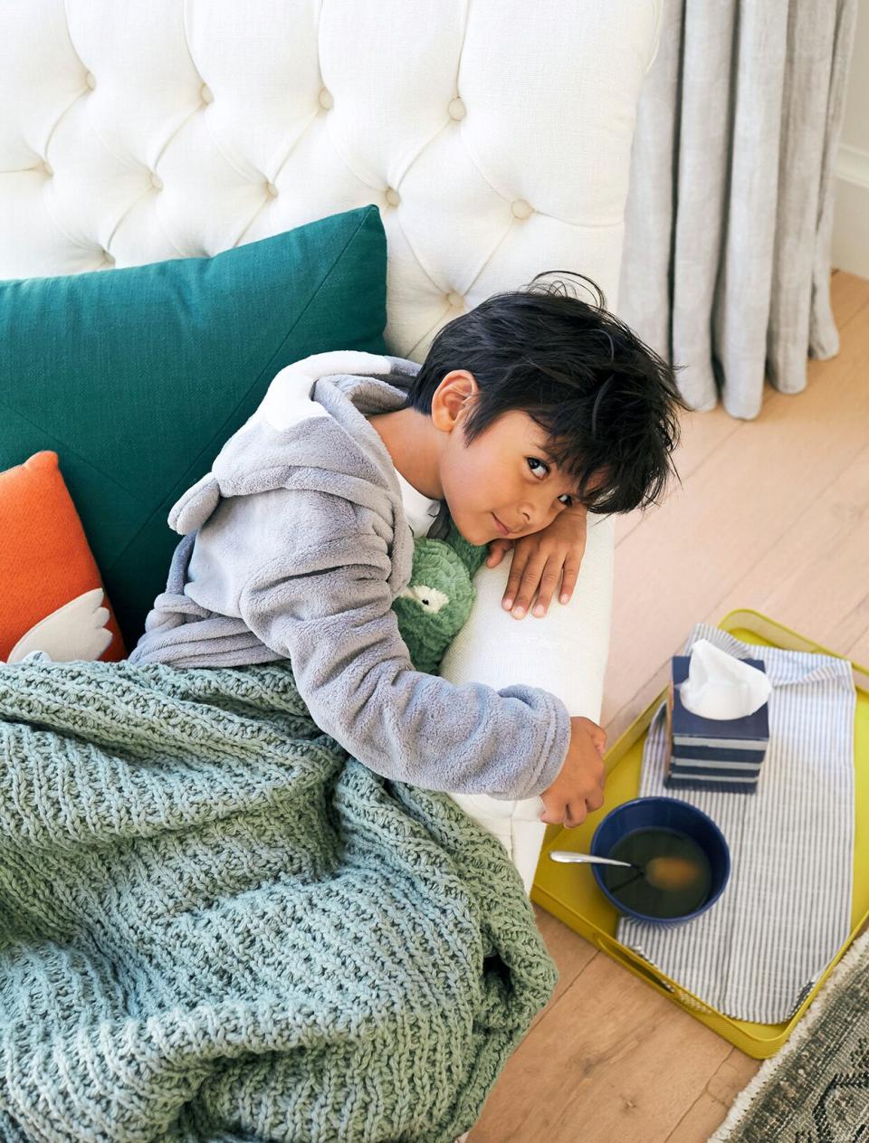 boy in robe lying on sofa with soup