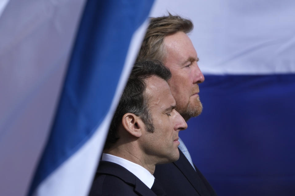 French President Emmanuel Macron, left, and Dutch King Willem-Alexander listen to national anthems outside the royal palace on Dam square in Amsterdam, Netherlands, Tuesday, April 11, 2023. French President Emmanuel Macron begins a two-day state visit to the Netherlands on Tuesday and is making a speech on his vision for the future of Europe. (AP Photo/Peter Dejong)