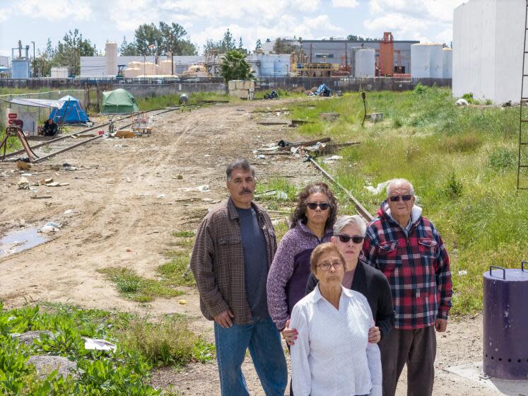 LOS ANGELES COUNTY, CA- APRIL 05: Jaime Sanchez, left; Maria Padilla, Esther Rojo, Stephanie Sanchez and Ruben Sanchez are among the residents of unincorporated Los Nietos who oppose a new permit for the hazardous waste facility Phibro-Tech (background) located in neighboring Santa Fe Springs. They have expressed health concerns because of the proximity. Photographed on Friday, April 5, 2024. (Myung J. Chun / Los Angeles Times)