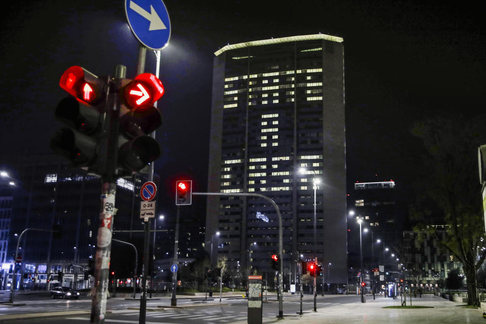 Office lights of the Lombardy region headquarters building in Milan, northern Italy, compose the Italian words 'State a casa' (Stay home), March 18, 2020. (AP Photo/Luca Bruno)