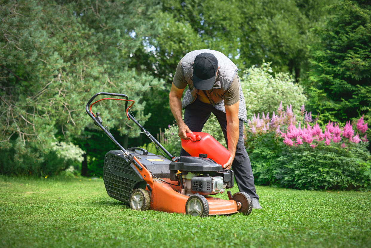 A man adds gasoline to a lawnmower. 