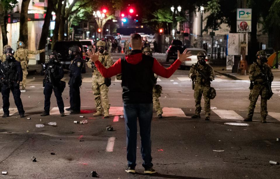 A lone man confronts a line of federal agents during protests near the federal courthouse in Portland, Oregon, in the early hours of July 24, 2020. They fired a teargas canister at his feet moments later.
