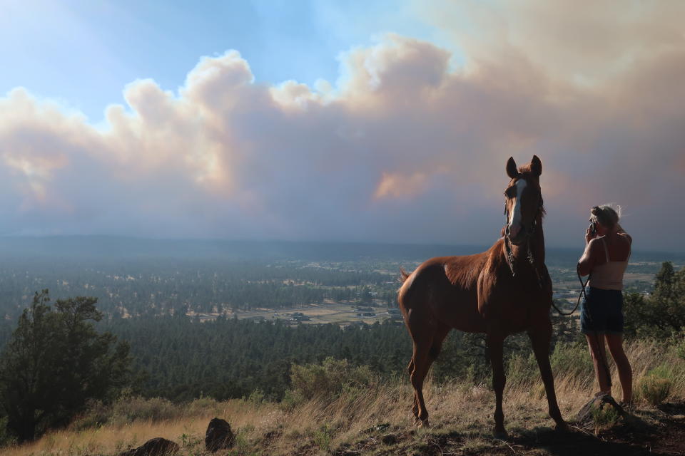 Janetta Kathleen and her horse, Squish, watch as smoke rises above neighborhoods on the outskirts of Flagstaff, Ariz., Sunday, June 12, casts a glow above neighborhoods. Evacuations have been ordered for homes in the area. Authorities say firefighters are responding to the wildfire about six miles north of Flagstaff that has forced evacuations. (AP Photo/Felicia Fonseca)