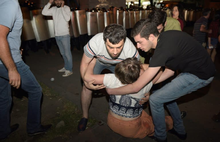 Opposition supporters help a woman during a protest near the besieged Erebuni police station in Yerevan late on July 29, 2016