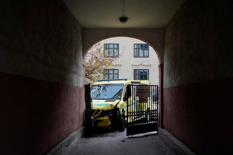 A damaged ambulance stands next to a building after an armed man who stole the vehicle was apprehended by police in Oslo