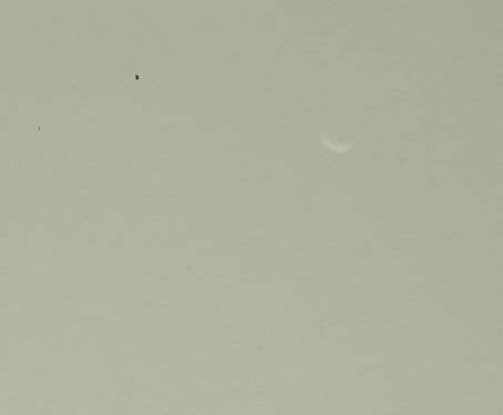 This close up from a photo by NASA's Mars rover Curiosity shows the Martian moon Phobos as a faint crescent in the Martian evening sky. The black blemish is the result of a bad pixel in the image data. Image released Sept. 26, 2012.