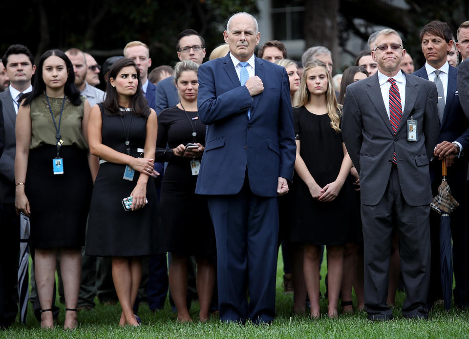 <p>White House Chief of Staff John Kelly (C) places his hand over his heart during the playing of “Taps” while joining members of the White House staff in observing a moment of silence on the south lawn of the White House at 8:37 A.M., the time the first tower was hit in the attacks of September 11th, on Sept. 11, 2018 in Washington, D.C. (Photo: Win McNamee/Getty Images) </p>