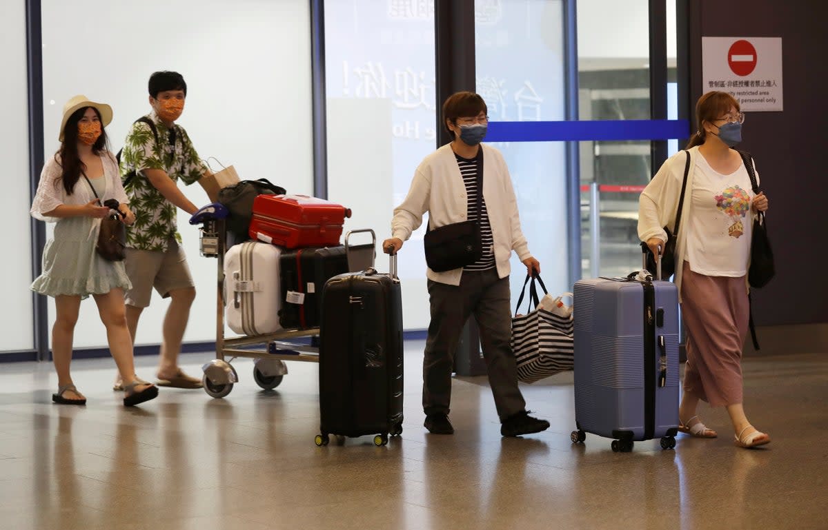 First group of foreign travellers arrive at Taoyuan International Airport in Taiwan since the state eased its restrictions  (AP)