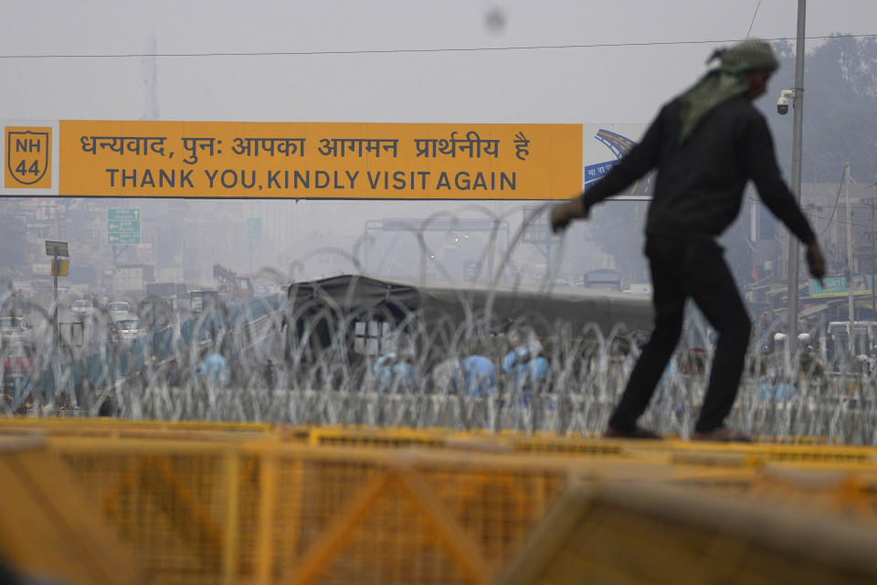 Workers put up barbed wire on top of barricades on a major highway at Singhu near New Delhi to stop thousands of protesting farmers from entering the capital, India, Tuesday, Feb.13, 2024. Farmers, who began their march from northern Haryana and Punjab states, are asking for a guaranteed minimum support price for all farm produce. (AP Photo/Manish Swarup)