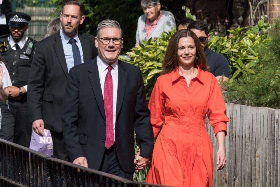 keir and victoria starmer holding hands while pictured on their way to vote