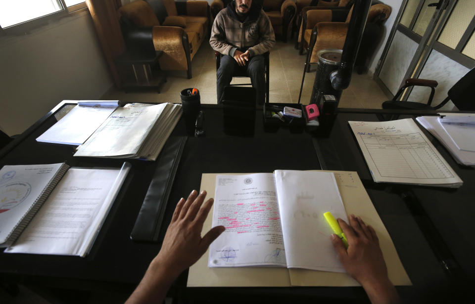 FILE - In this April 3, 2018 file photo, a 19-year-old Syrian former member of the Islamic State group, who declined to be identified, sits opposite a panel of judges in the courtroom of a Kurdish-run terrorism court, in Qamishli, north Syria. The IS could get a new injection of life if conflict erupts between the Kurds and Turkey in northeast Syria as the U.S. pulls its troops back from the area. The White House has said Turkey will take over responsibility for the thousands of IS fighters captured during the long campaign that defeated the militants in Syria. But it’s not clear how that could happen. (AP Photo/Hussein Malla, File)