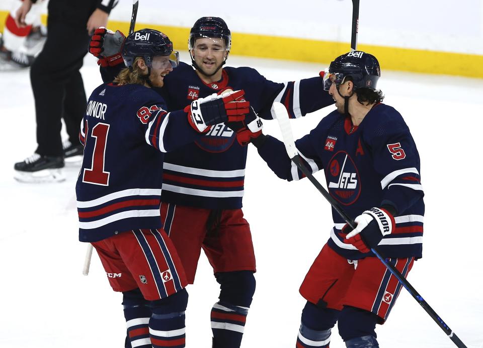 Winnipeg Jets' Kyle Connor (81), Neal Pionk (4) and Brenden Dillon (5) celebrate after Connor's goal against the Detroit Red Wings during first-period NHL hockey action in Winnipeg, Manitoba, Friday, March 31, 2023. (John Woods/The Canadian Press via AP)