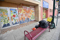 A man sits near a colorful painted boarded-up business, Thursday, June 18, 2020 in Minneapolis. Scores of businesses along Lake Street remain boarded up following riots, fires and looting. Floyd died in police custody after video shared online by a bystander showed former officer Derek Chauvin kneeling on Floyds' neck during his arrest as he pleaded that he couldn't breathe. (AP Photo/Jim Mone)