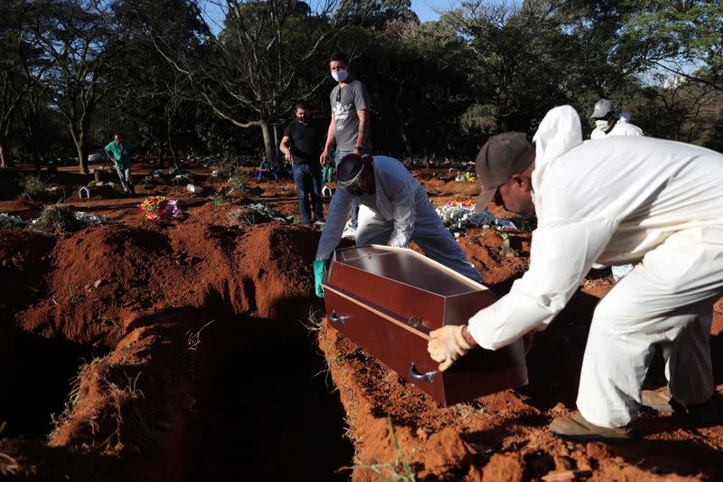 Sepultureros con trajes protectores se preparan para enterrar el ataúd de Izolina de Sousa, de 85 años, quien murió a causa de la enfermedad por coronavirus (COVID-19), en el cementerio de Vila Formosa, el cementerio más grande de Brasil, en Sao Paulo