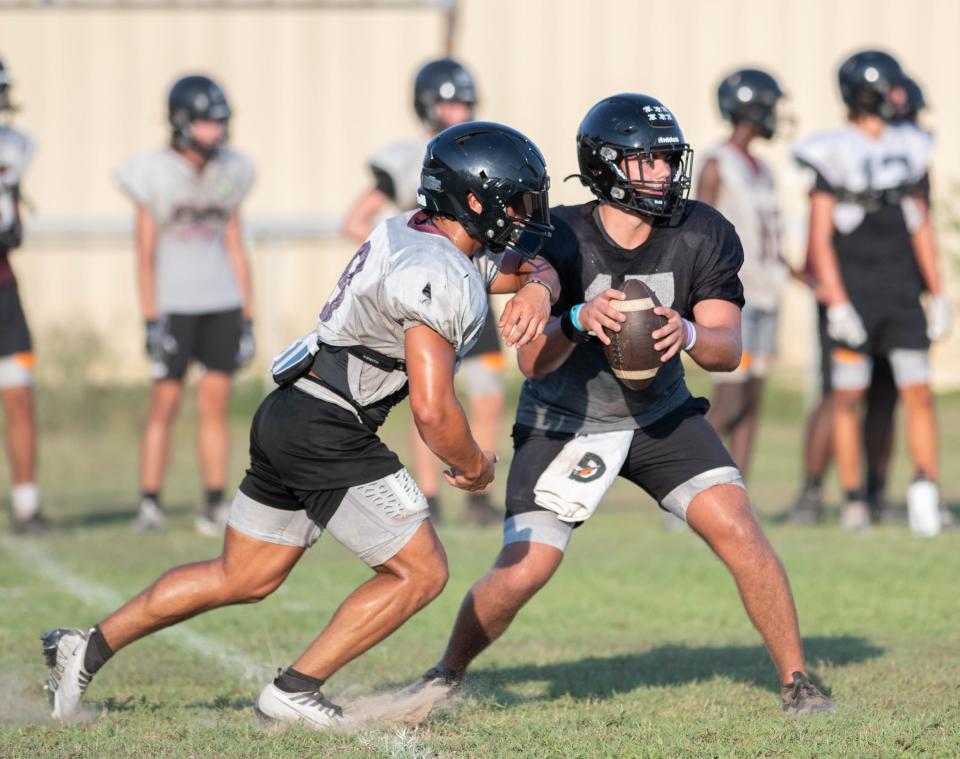 Quarterback Hunter Pfiester (17) fakes the handoff during football practice at Navarre High School on Wednesday, Aug. 2, 2023.