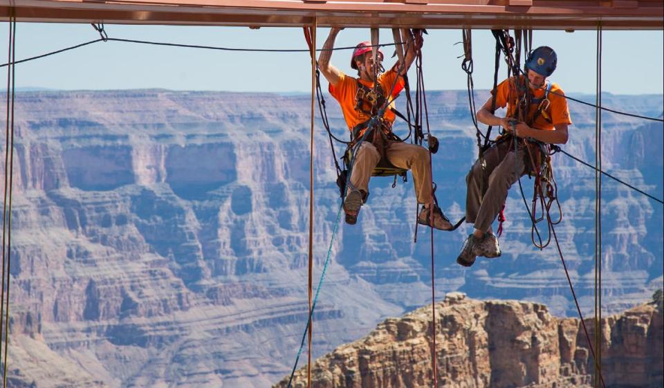 In this Tuesday, March, 25, 2014 photo provided by Abseilon USA via AZ Photos, technicians dangle from a series of ropes before polishing the underside glass at Grand Canyon Skywalk in Hualapai Reservation, Ariz. The more than 40 panes of glass underneath the horseshoe-shaped bridge on the Hualapai reservation aren’t easily accessible. The structure juts out 70 feet from the edge of the Grand Canyon, offering visitors a view of the Colorado River 4,000 feet below. (AP Photos/Abseilon USA, AZ Photos, George Walsh)