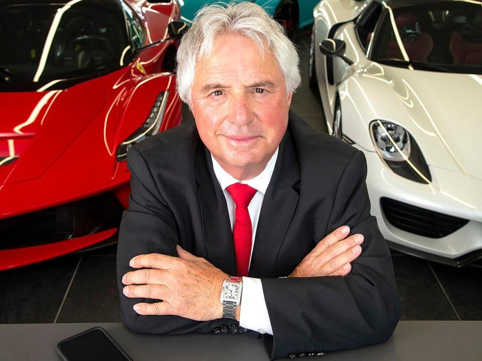 man sitting in front of two supercars