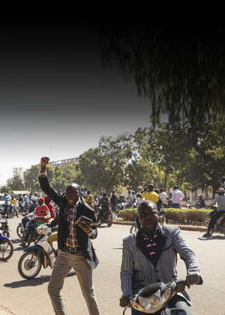 Des passants saluent les soldats qui gardent le siège de la télévision publique à Ouagadougou, la capitale du Burkina Faso, le 24 janvier 2022, quelques heures après l’annonce du coup d’État.. Photo Malin Fezehai/The New York Times