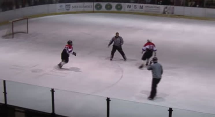 A referee is chased down by a pair of teen hockey players. (Screen grab via YouTube)