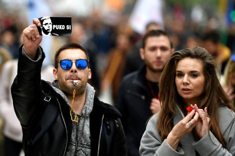 A protestor holds a sticker showing Aleksandar Vucic and reading: "You are finished"