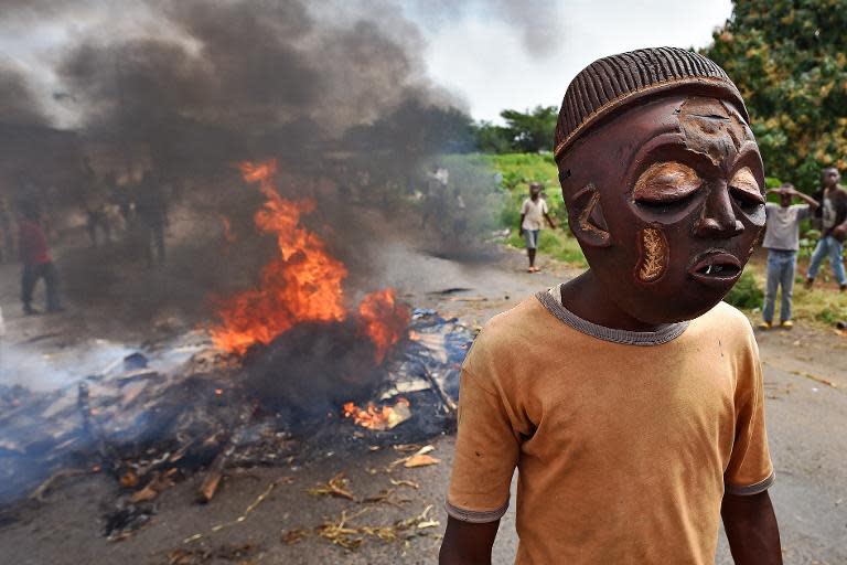 A protestor opposed to Burundian President Pierre Nkurunziza seeking a third consecutive term in office, wears a mask near a burning barricade in the Kinama neighborhood of Bujumbura on May 25, 2015