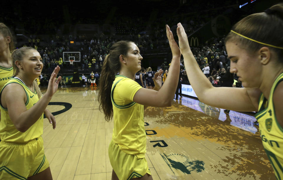 Oregon's Jaz Shelley, left, Taylor Chavez and Sabrina Ionescu, right congratulate each other after winning their NCAA college basketball game against Utah State 108-52 in Eugene, Ore., Wednesday, Nov. 13, 2019. (AP Photo/Chris Pietsch)