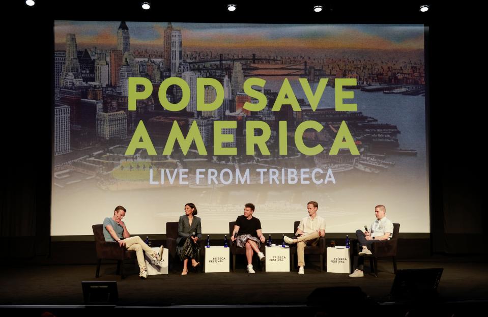Pod Save America hosts speaking at a panel in 2023.