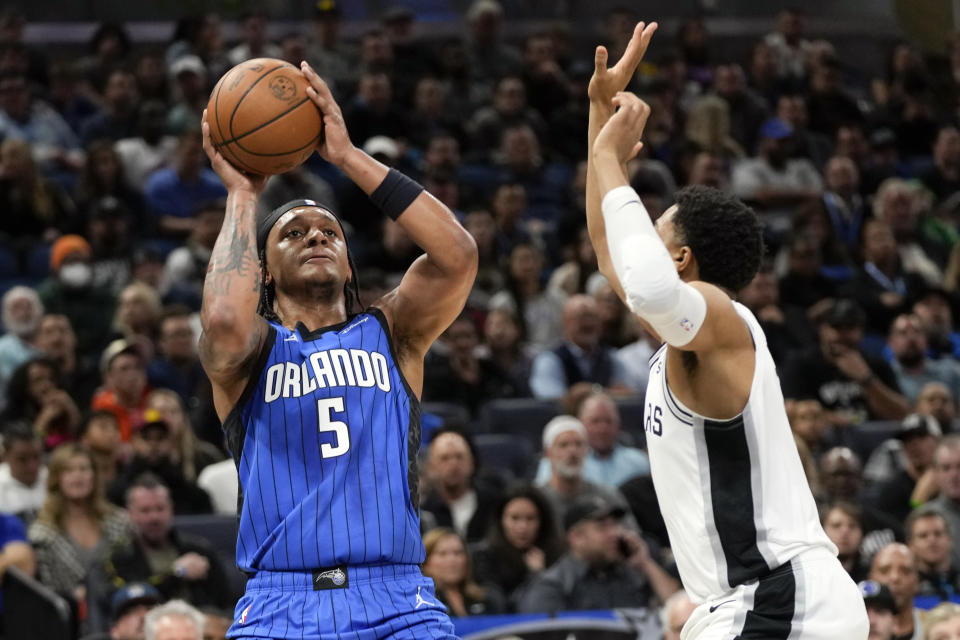 Orlando Magic forward Paolo Banchero (5) looks to shoot over San Antonio Spurs forward Keldon Johnson, right, during the first half of an NBA basketball game, Thursday, Feb. 8, 2024, in Orlando, Fla. (AP Photo/John Raoux)