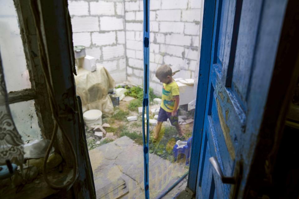 A boy is seen in a yard through a door.