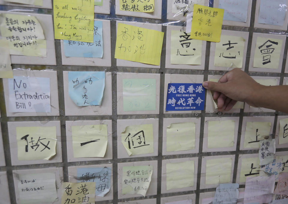 Hong Tsun-ming, a Taiwanese of Hong Kong descent, puts a "Free Hong Kong, Revolution Now" sticker on the Lennon Wall in Taichung city, Central Taiwan, on Nov. 30, 2023. As Taiwan’s presidential election approaches, many immigrants from Hong Kong, witnesses to the alarming erosion of civil liberties at home, are supporting the ruling Democratic Progressive Party.(AP Photo/Chiang Ying-ying)