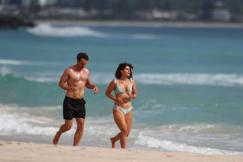 A man and a woman run along Coolangatta Beach on the Gold Coast before it was shut this week.