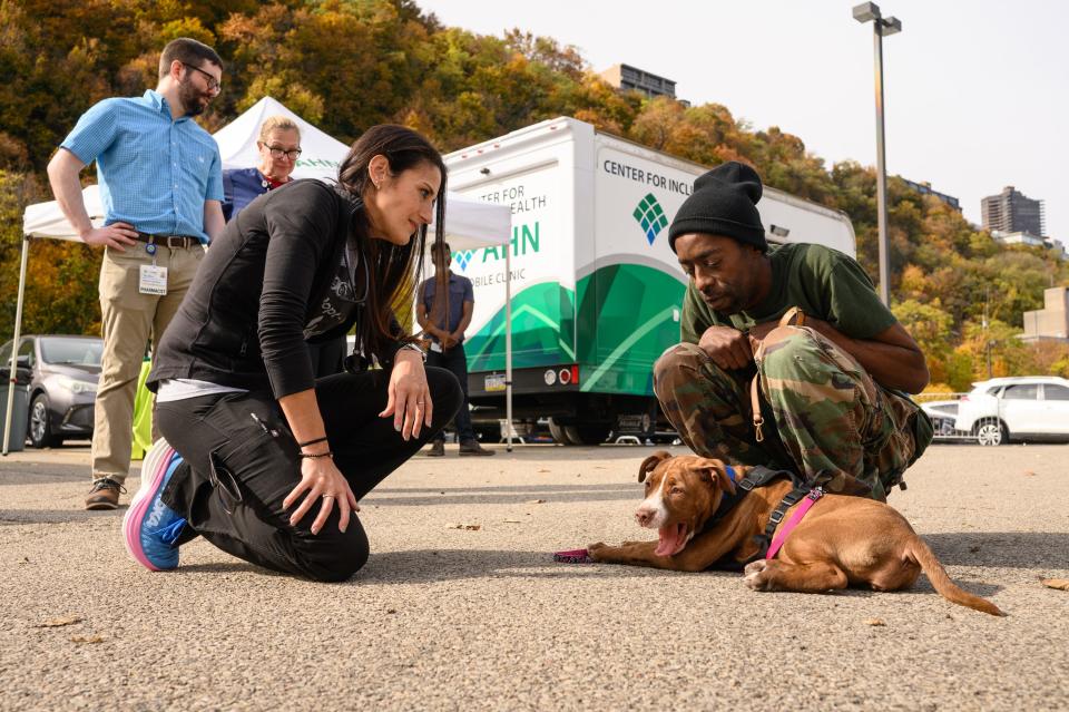 Terrue Scoggins, 41, holds his dog, Katana, as he talks with Dr. Ariella Samson, executive director of Humane Animal Rescue of Pittsburgh, at the new pilot program that uses mobile clinics to treat people and their pets on Oct. 26 in Pittsburgh.