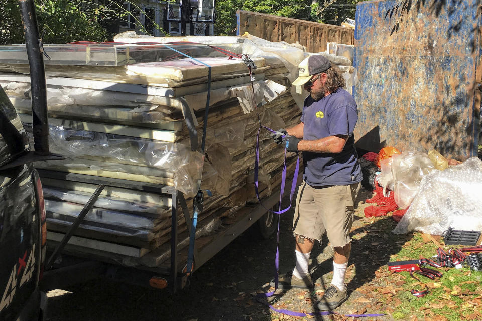 George Martin secures to a trailer paintings by Francis Hines that were found in a dumpster, Sept. 23, 2017, in Watertown, Conn. After fading into obscurity, Hines, who died in 2016, is again gaining attention after hundreds of his paintings were rescued by a car mechanic from a dumpster in Connecticut. An exhibit of that art will open May 5, 2022, at the Hollis Taggart galley in Southport, which is known for showing the works of lost or forgotten artists. (Scott Whipple via AP)
