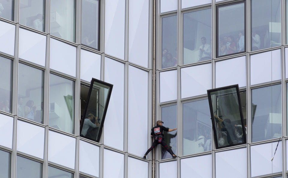 People look out of their windows as French urban climber Alain Robert, known as 'Spiderman', climbs up the 231 meter high (758 feet) First Tower, the tallest skyscraper in France, in the La Defense business district in Courbevoie, outside Paris, Thursday, May 10, 2012. (AP Photo/Michel Euler)