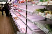 A shopper wearing a protective face mask, following an outbreak of the coronavirus disease (COVID-19), is seen next to empty shelves at a supermarket in Tokyo