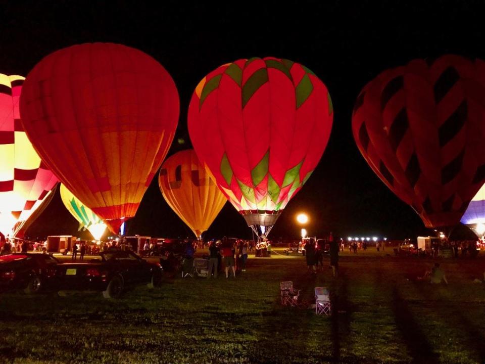 Some hot air balloons site idle for visitors to admire during an evening show at the 2022 White Sands Balloon Invitational