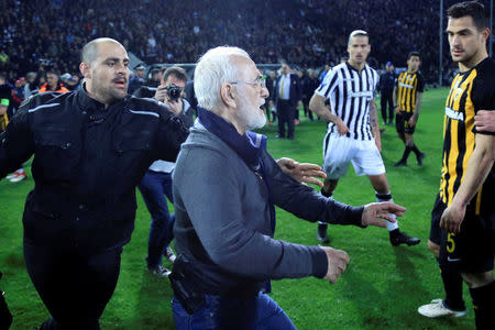 Russian-born Greek businessman and owner of PAOK Salonika, Ivan Savvides (C), pictured with what appears to be a gun in a holster, enters the pitch after the referee annulled a goal of PAOK during their soccer match against AEK Athens in Toumba Stadium in Thessaloniki, Greece, March 11, 2018. Intimenews via REUTERS