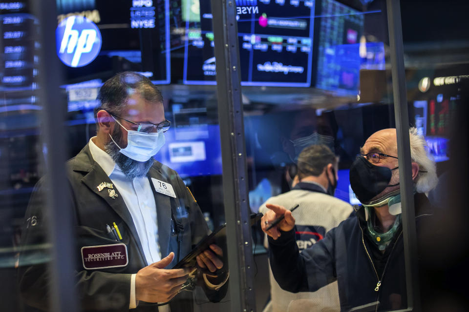 In this photo provided by the New York Stock Exchange, traders Aman Patel, left, and Peter Tuchman work on the floor, Friday, Feb 26, 2021. Stocks wobbled between small gains and losses on Wall Street Friday as rising technology stocks offset a slide in banks and energy companies. (Courtney Crow/New York Stock Exchange via AP)