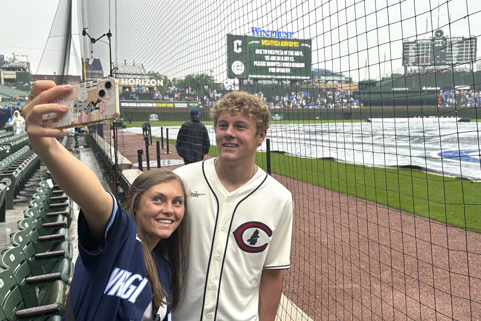 Grace and Nate Stevens from Barrington, Ill., take a selfie during a weather delay before a baseball game between the Chicago Cubs and the Cleveland Guardians Saturday, July 1, 2023, at Wrigley Field in Chicago. (AP Photo/Charles Rex Arbogast)