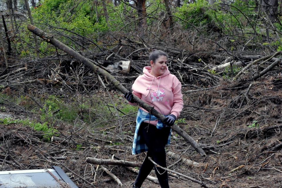 Isabella Elliott carries a tree limb to a waiting pile of storm debris. She spent time with fellow Edgewood Middle School seventh graders helping to clean up parts of the Killbuck Wildlife area.