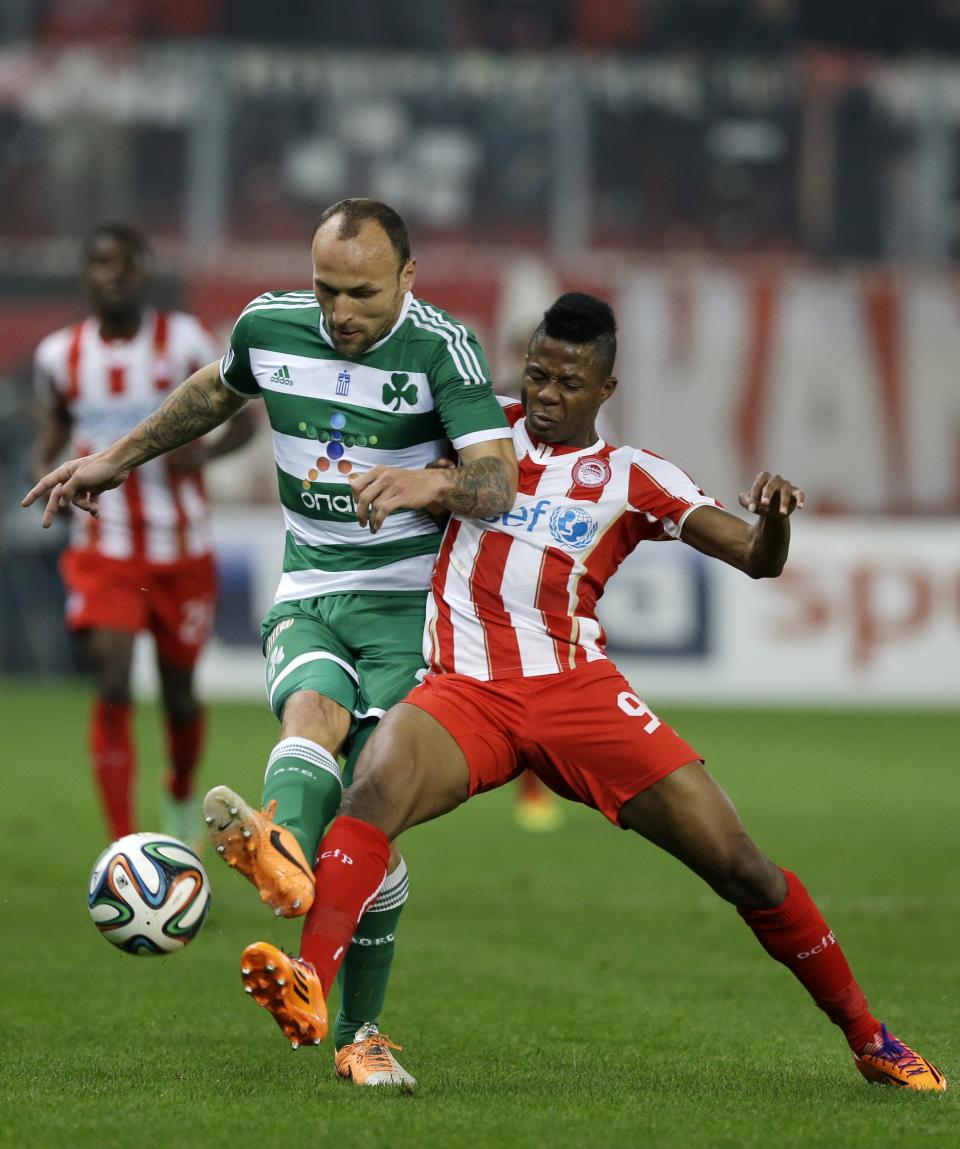 Olympiakos' Michael Olaitan, right, fights for the ball with Panathinaikos' Gordon Schildenfeld during a Greek League soccer match at Georgios Karaiskakis stadium, in Piraeus port, near Athens, on Sunday, March 2, 2014. (AP Photo/Thanassis Stavrakis)