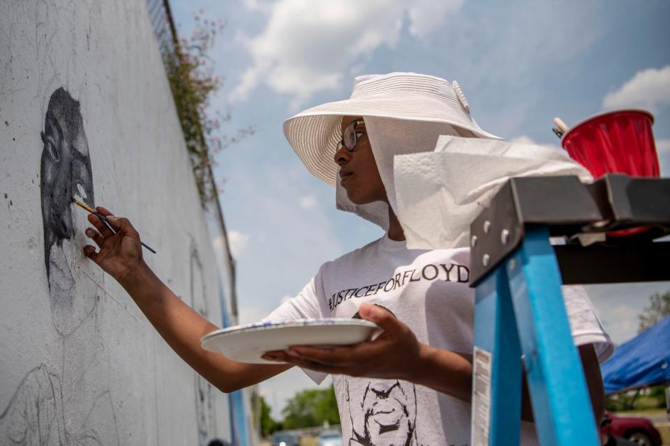 Jamari Taylor works on a mural for Color the Creek's Black Lives Matter project on Saturday, June 20, 2020 on the corner of Dickman Rd. and Riverside Dr. in Battle Creek.